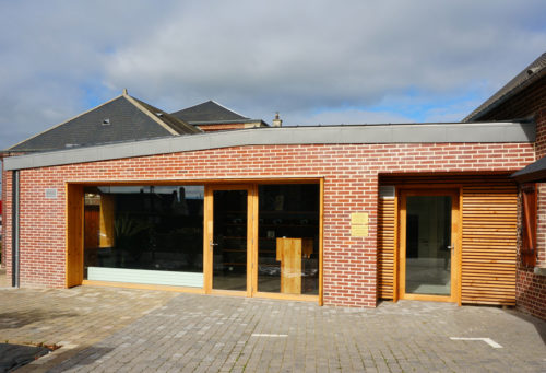 Construction d'un cabinet médical et d'un commerce par Atelier Cosme Architecture à Saint-Vigor-d'Ymonville. Vue de la façade à double entrée.